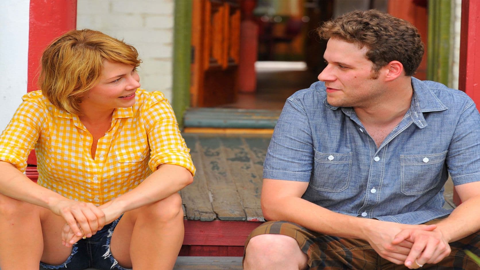 Die Schauspieler Michelle Williams und Seth Rogen sitzen nebeneinander auf einer Treppe.