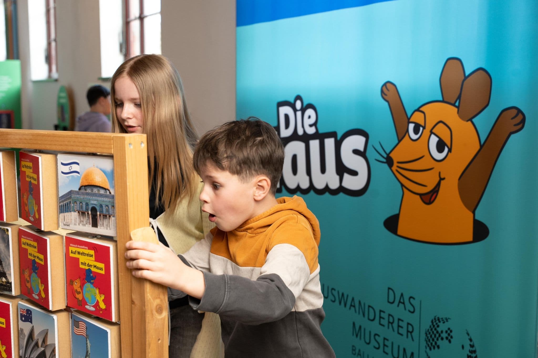 Zwei Kinder stehen vor einem Bücherregal. Im Hintergrund hängt ein Plakat mit „Die Maus”. | Bildquelle: WDR Zwei Kinder stehen vor einem Bücherregal. Im Hintergrund hängt ein Plakat mit „Die Maus”.